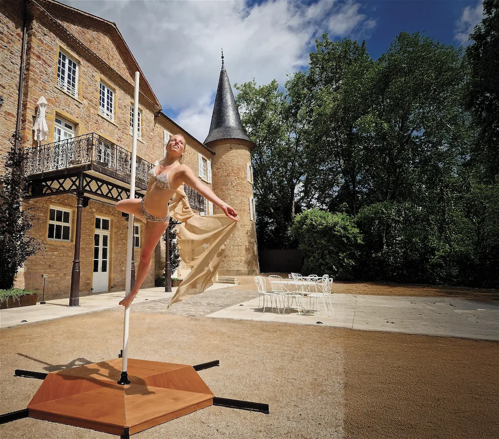 Nathalie posant sur sa barre de pole dance devant un château