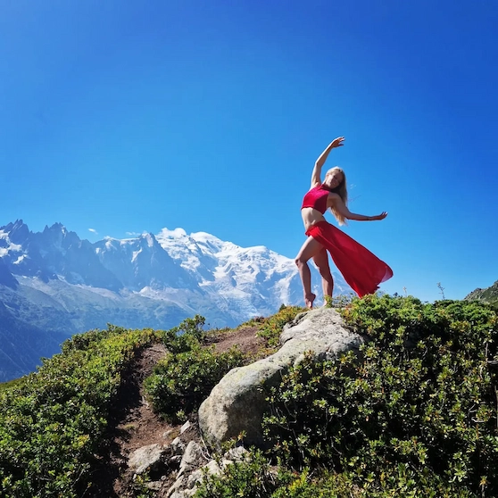 Madame Passions posant en tenue de pole dance, avec des montagnes en arrière-plan